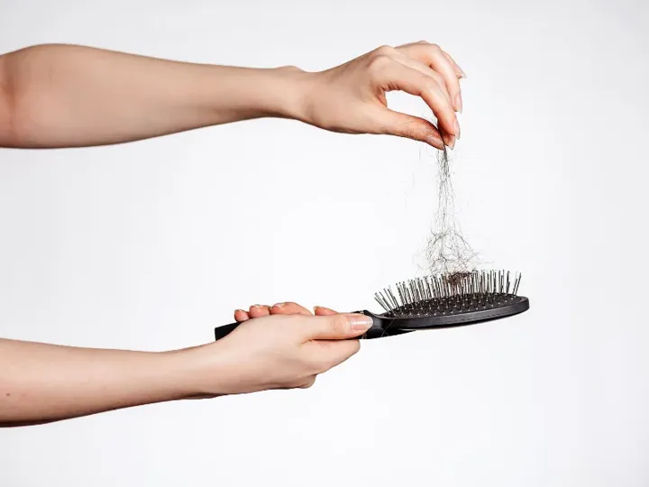 Hand holding a brush with fallen hair in it