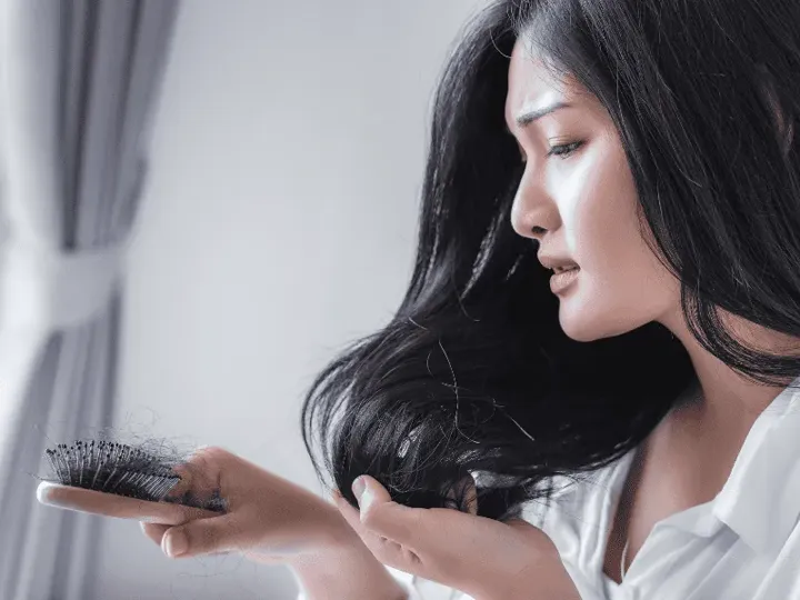 Woman looking at hair fall in her brush