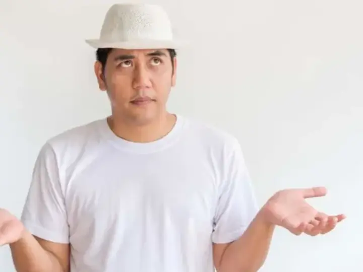 Man wearing a hat with his palms turned up in question